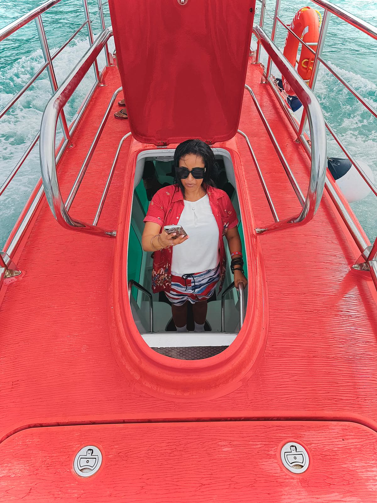 Top-down view of the semi-submarine deck with a guest stepping down through the open hatch to the viewing cabin